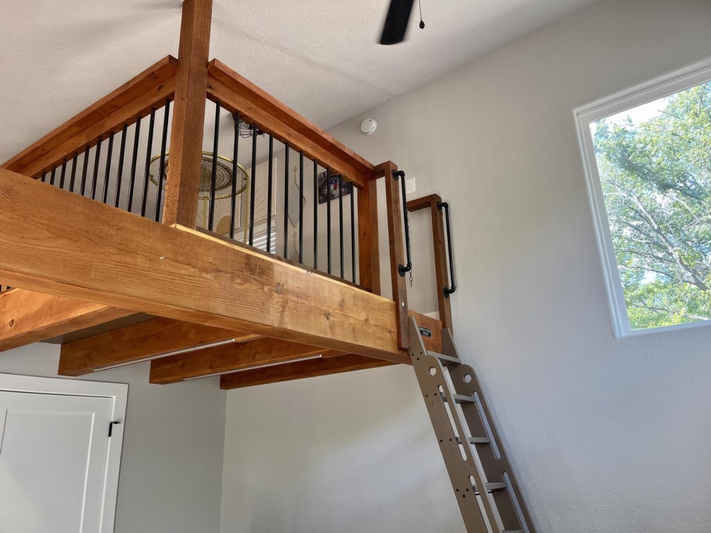 Library ladder leads to a unique sleeping loft with a queen sized bed (watch your head!)
