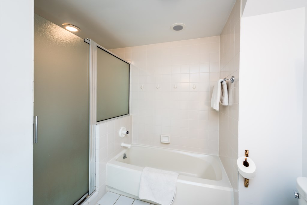 Primary bathroom with tub and large tiled shower with built-in bench. 