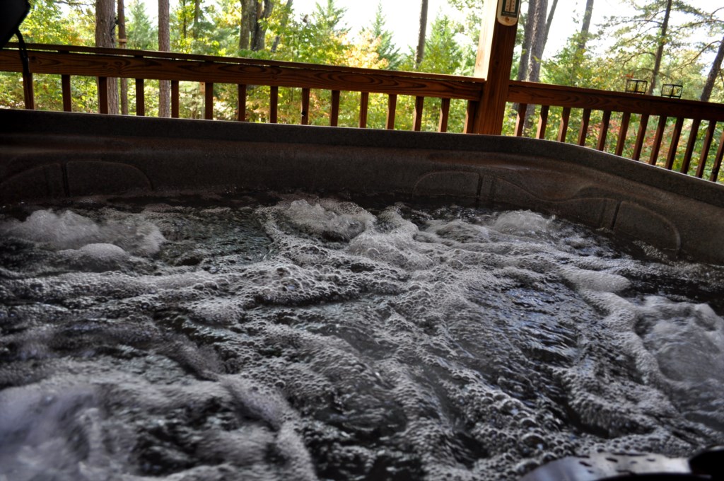 Hot tub on the covered back porch next to outdoor fireplace