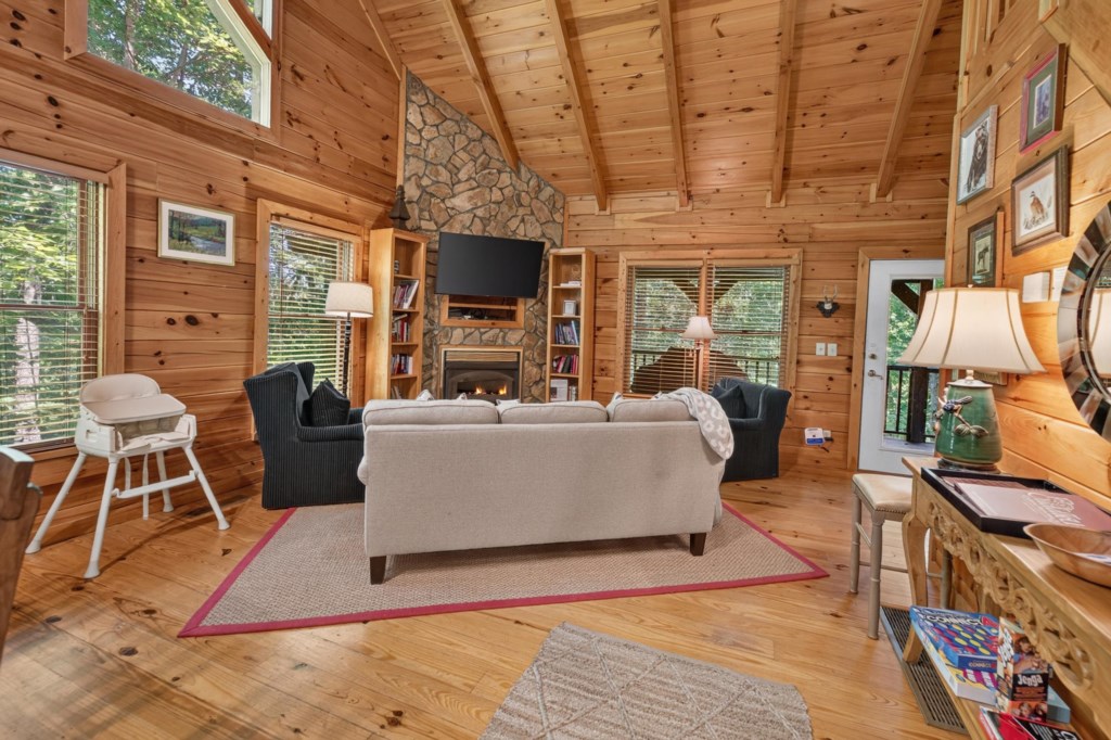 Cozy living room with a stone fireplace and rustic wood paneling, perfect for relaxation.