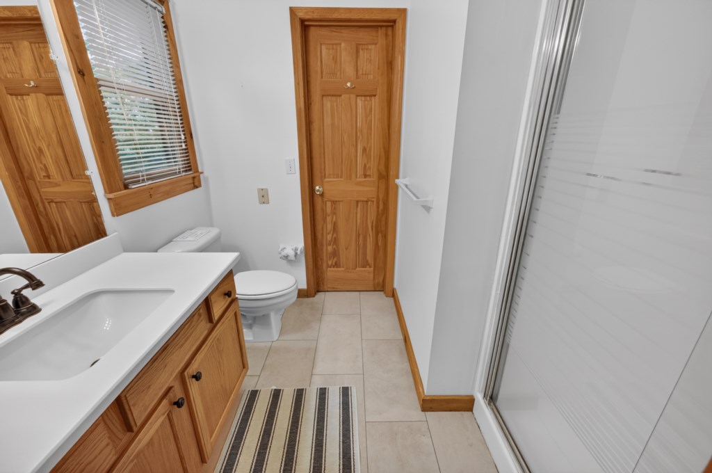 Bright bathroom with spacious shower and natural wood accents.