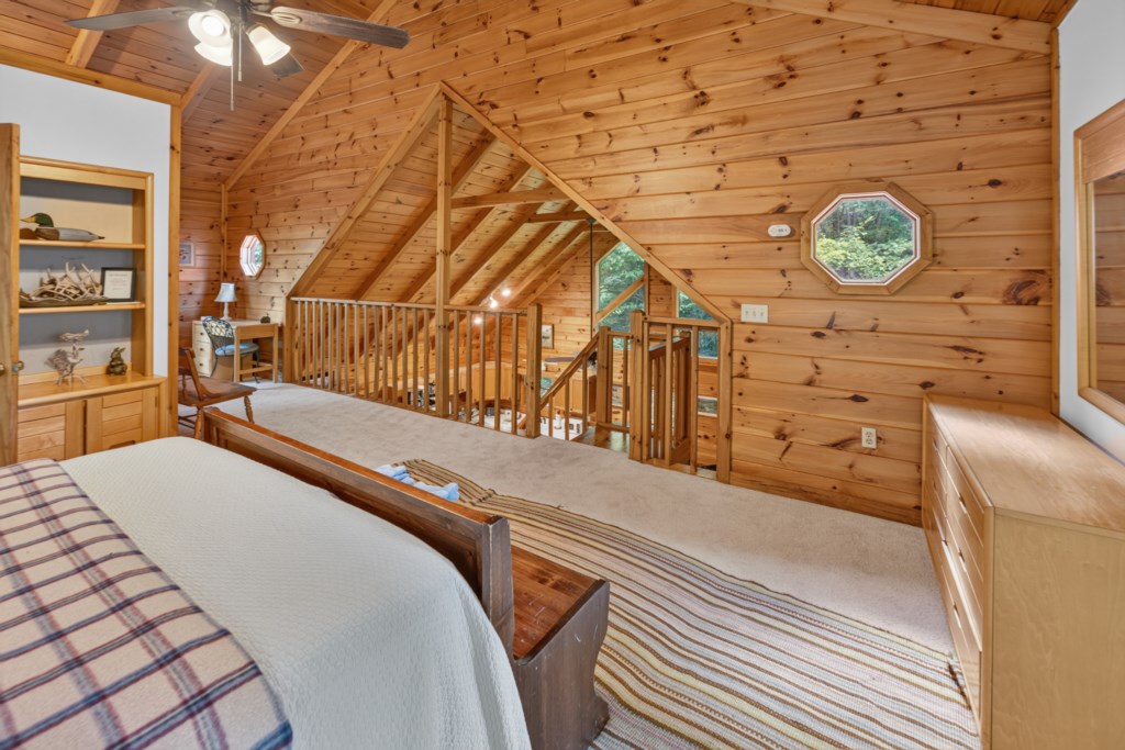 Charming loft bedroom with rustic wood paneling and cozy reading nook.