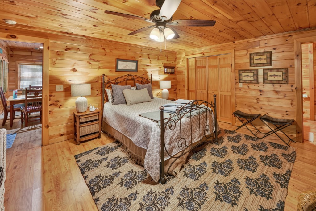 Cozy rustic bedroom with wood paneling and a charming wrought iron bed.