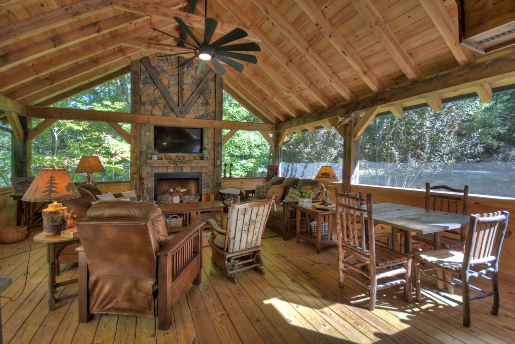 Living area on the covered porch with a tv (seasonal use) and a seasonal gas log fireplace!