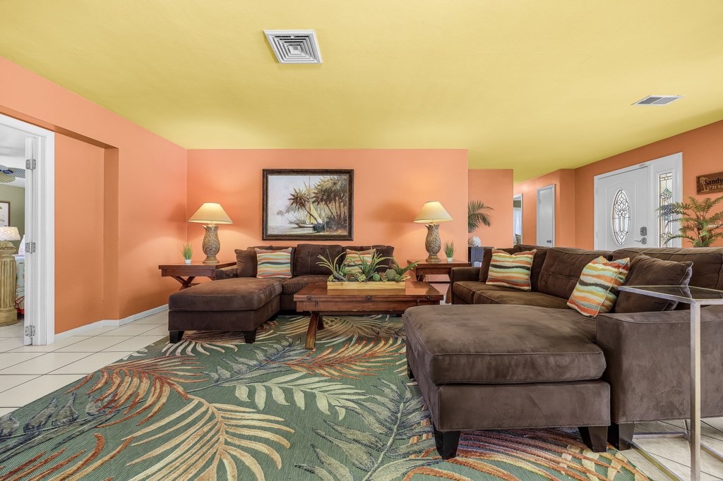 Vibrant living room with plush sectionals and tropical decor, perfect for relaxation.