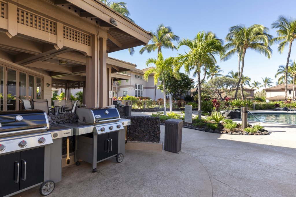 Outdoor grilling area with poolside views and lush tropical landscaping.