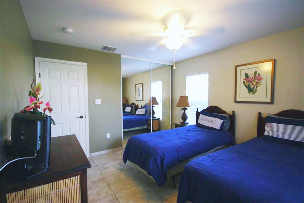 Twin bedroom with calming green walls and floral artwork, ideal for relaxation.