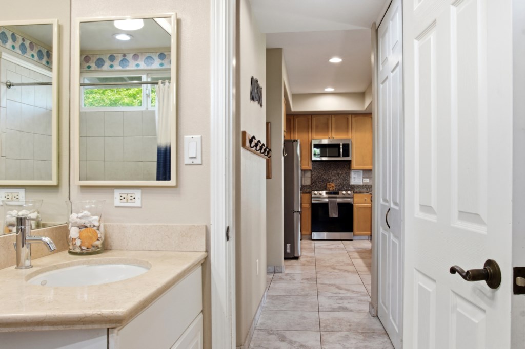Modern bathroom with a spacious vanity, leading to a sleek kitchen.