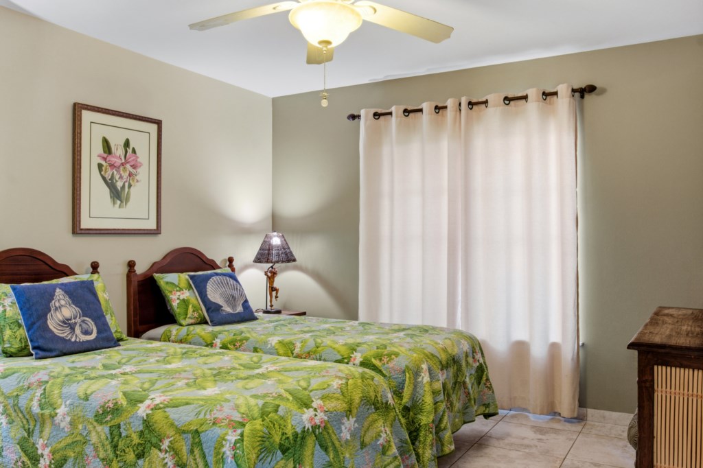 Charming twin bedroom with tropical decor and soft lighting for a relaxing stay.