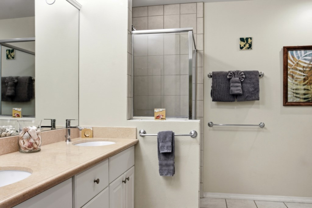 Modern bathroom with dual sinks, elegant decor, and a spacious glass-enclosed shower.