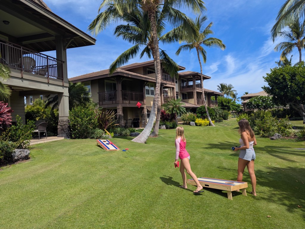Spacious lawn with cornhole game, ideal for outdoor fun and relaxation.
