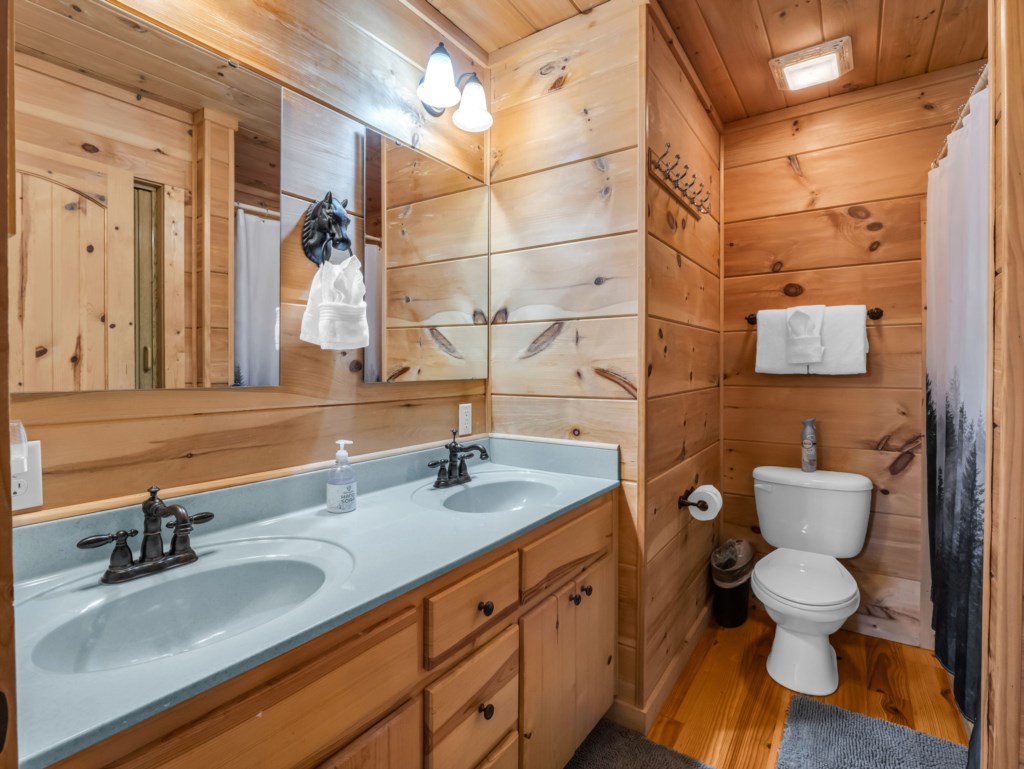 Rustic bathroom with dual sinks and wood paneling for a cozy cabin feel.
