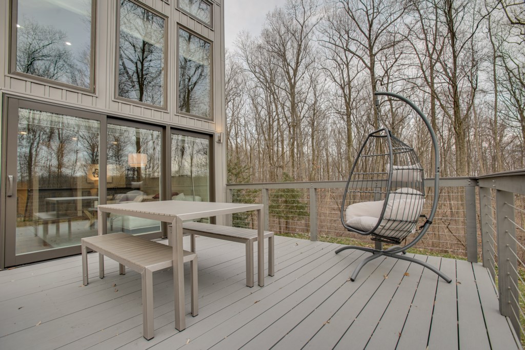 Right off the living room is this Beautiful Deck featuring a table with 2 benches, 2 Egg Chairs and a Grill. 