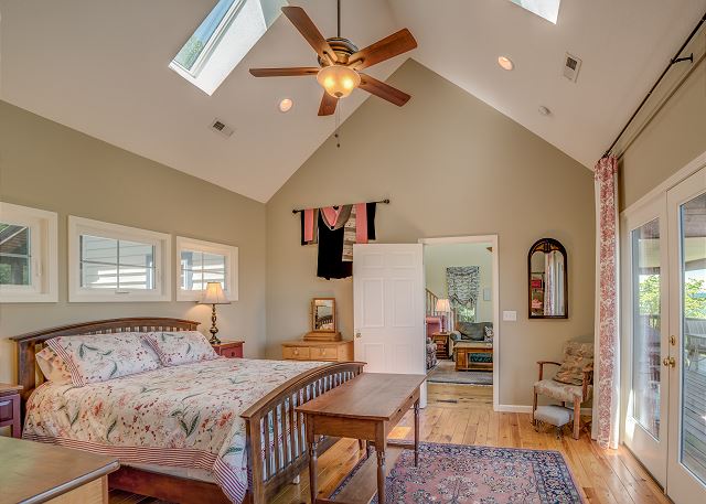 Primary King Bedroom on main level has cathedral ceiling with skylights, private bath and glass doors out to deck
