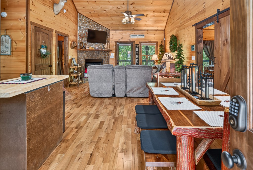 Rustic open-plan living and dining area with cozy fireplace and woodland decor.