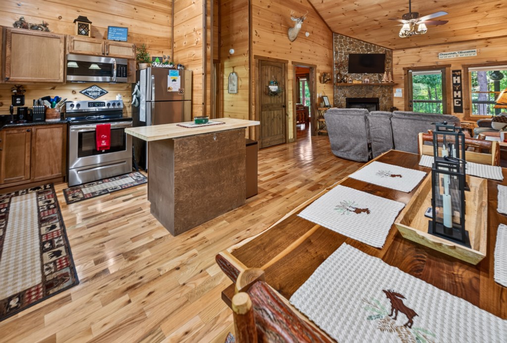 Rustic open-concept kitchen and living area with cozy fireplace and wood accents.