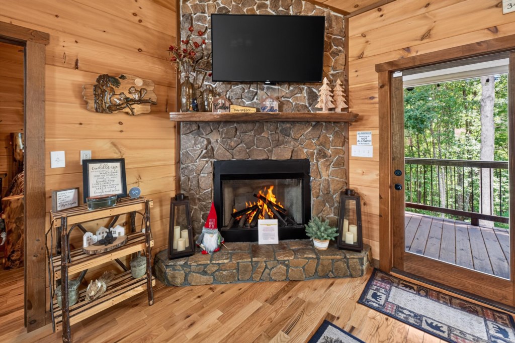 Cozy living area with a stone fireplace and forest views from the deck.