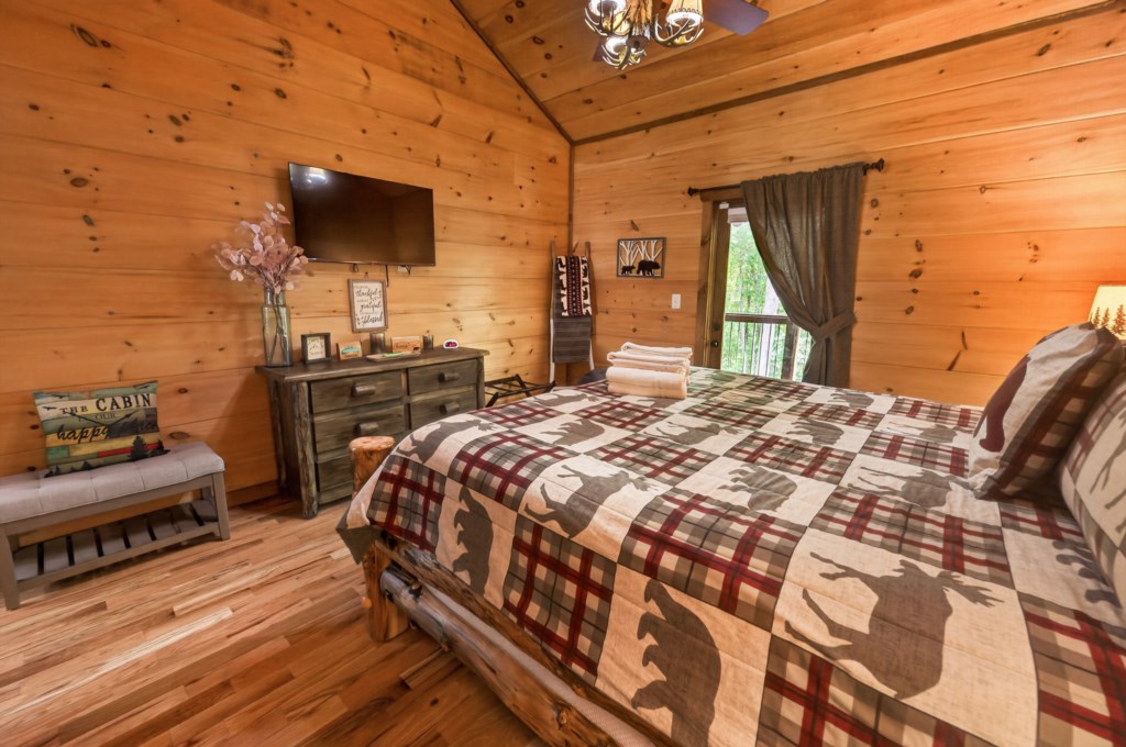 Rustic bedroom with wood paneling and forest views, perfect for a cozy cabin retreat.