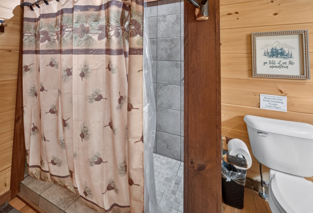 Rustic bathroom with pinecone shower curtain and cabin-themed decor.