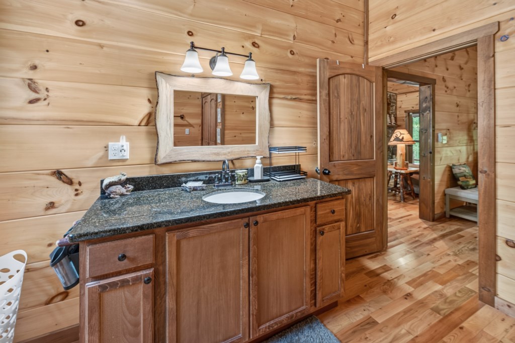 Rustic bathroom with wooden accents and a spacious granite countertop.