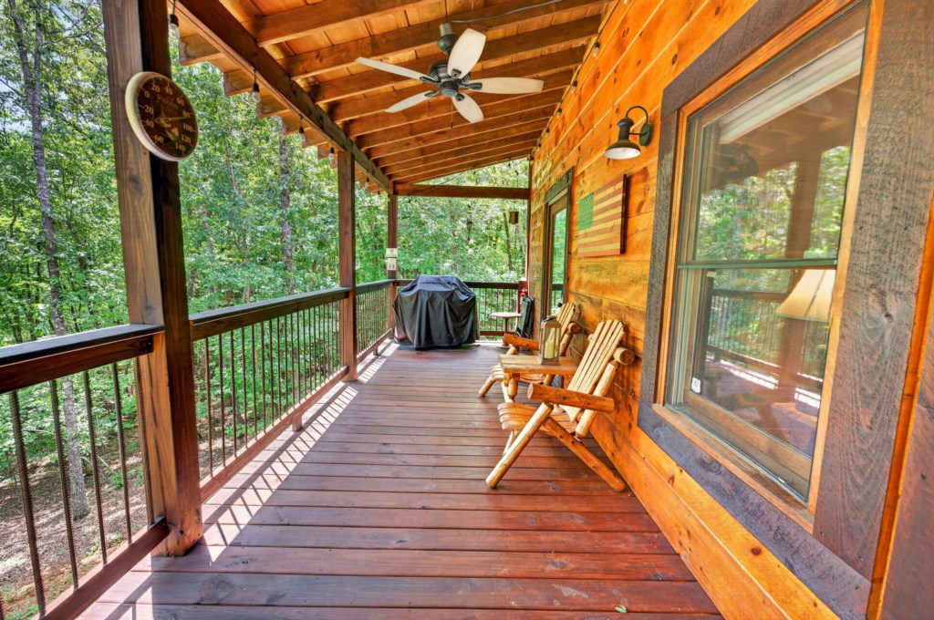 Charming wooden deck with forest views, perfect for relaxing in Adirondack chairs.