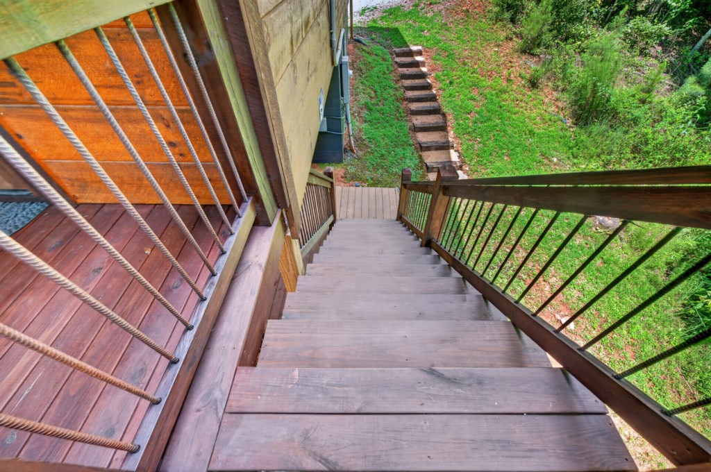 Rustic wooden stairs leading to a scenic outdoor space with lush greenery.