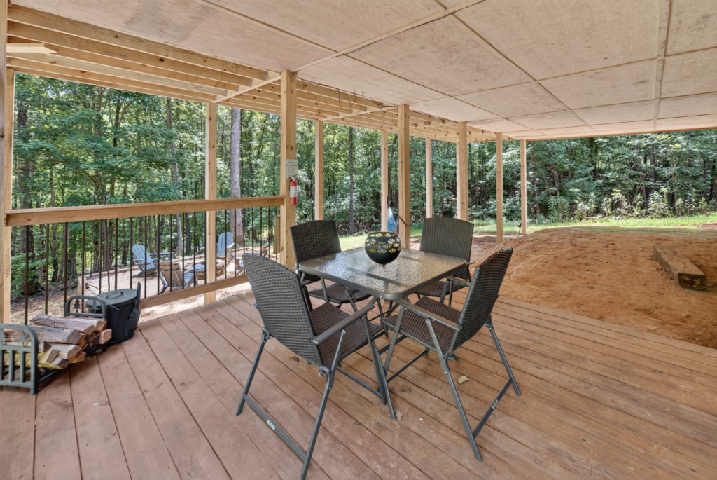 Covered outdoor deck with forest views, perfect for relaxing or dining al fresco.