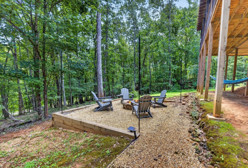 Wooded firepit area with Adirondack chairs, perfect for cozy evenings under the stars.
