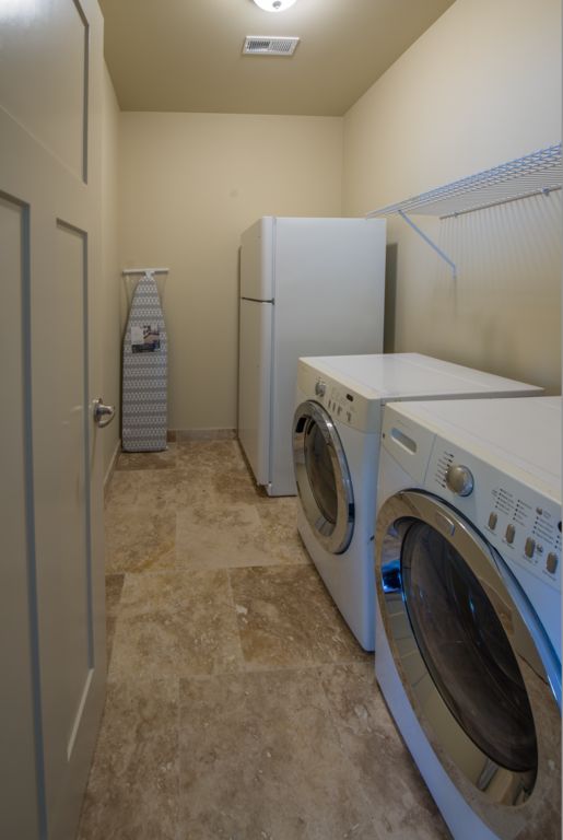 Laundry room with a full size refrigerator, washer and dryer. Plus Iron and ironing board