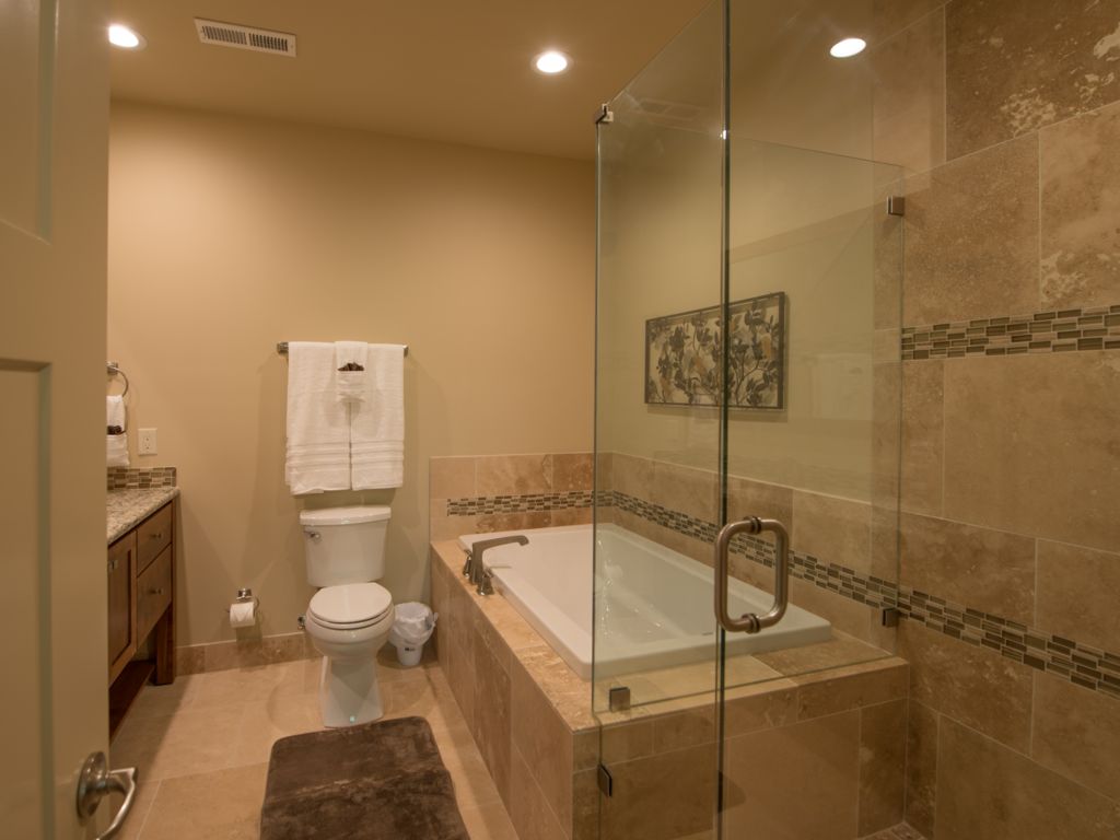 Master bath #1 features a custom natural stone walk-in shower and soaking tub. Relax. Soak. Unwind.