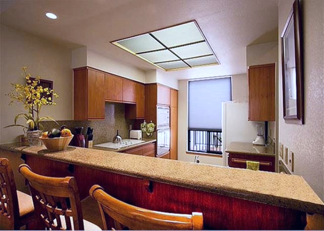 Well-equipped kitchen with wooden cabinets and a breakfast bar, ideal for quick meals or social cooking.