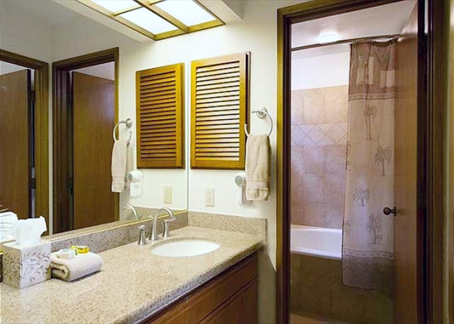 Well appointed bathroom featuring a large mirror, granite countertops, and an inviting, glass enclosed shower.