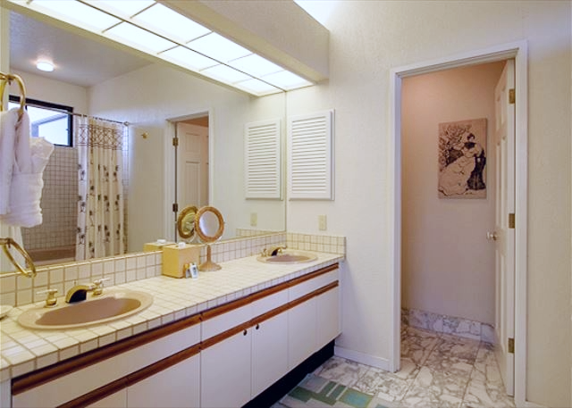 Spacious double vanity bathroom with tiled countertops and a separate tub shower area.
