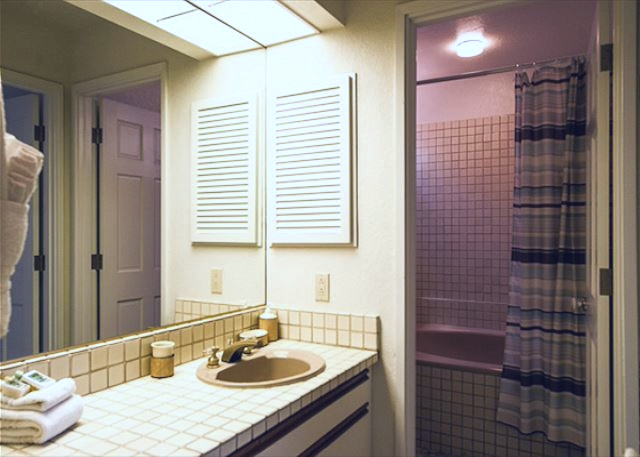 Bright bathroom with retro tile countertops and a separate tub shower combo for added convenience.