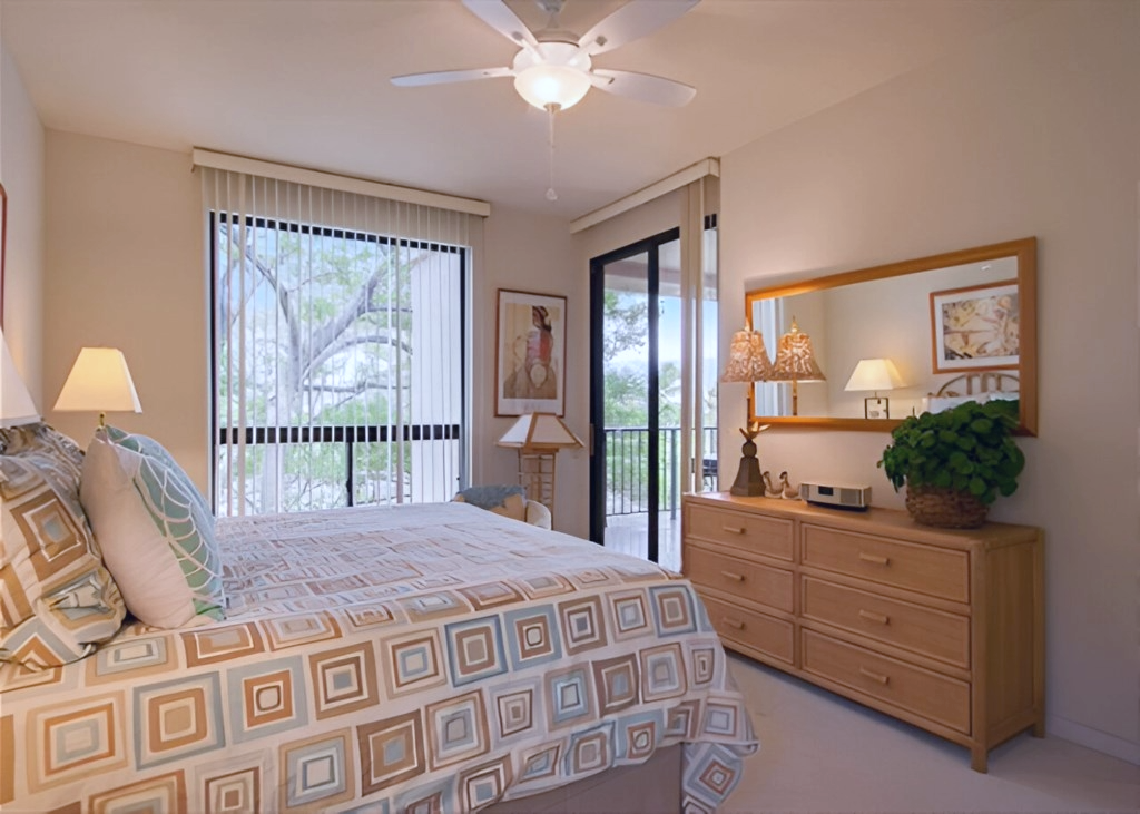 Bright and inviting bedroom with balcony access, stylish patterned bedding, and nature filled views.