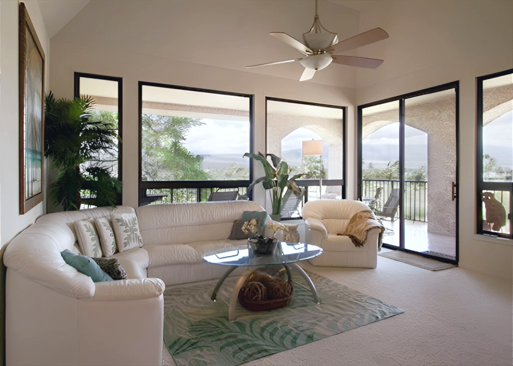 Bright and airy living room with panoramic views, plush white seating, and access to a breezy lanai.