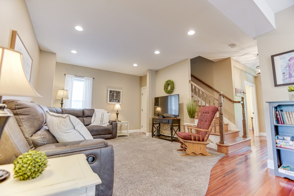 Spacious living room with large TV! Corner doorway to basement and stairwell to the 2nd floor
