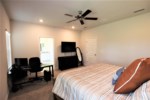 King primary bedroom with ceiling fan, flat screen television, and attached bath