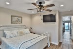 King guest room with ceiling fan, closet access, flat screen tv, and half bath