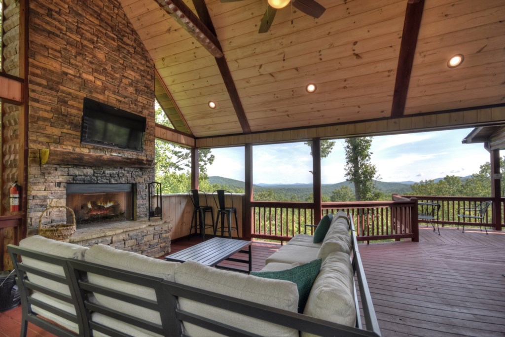 Main level porch with sitting area, small bar, tv and fireplace 