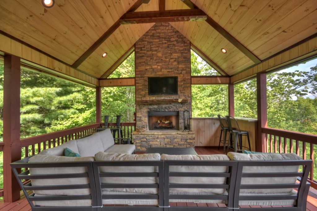 Main level porch with sitting area, small bar, tv and fireplace 