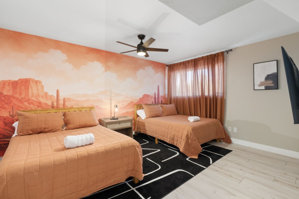 Desert-themed bedroom with two cozy beds and vibrant mural.