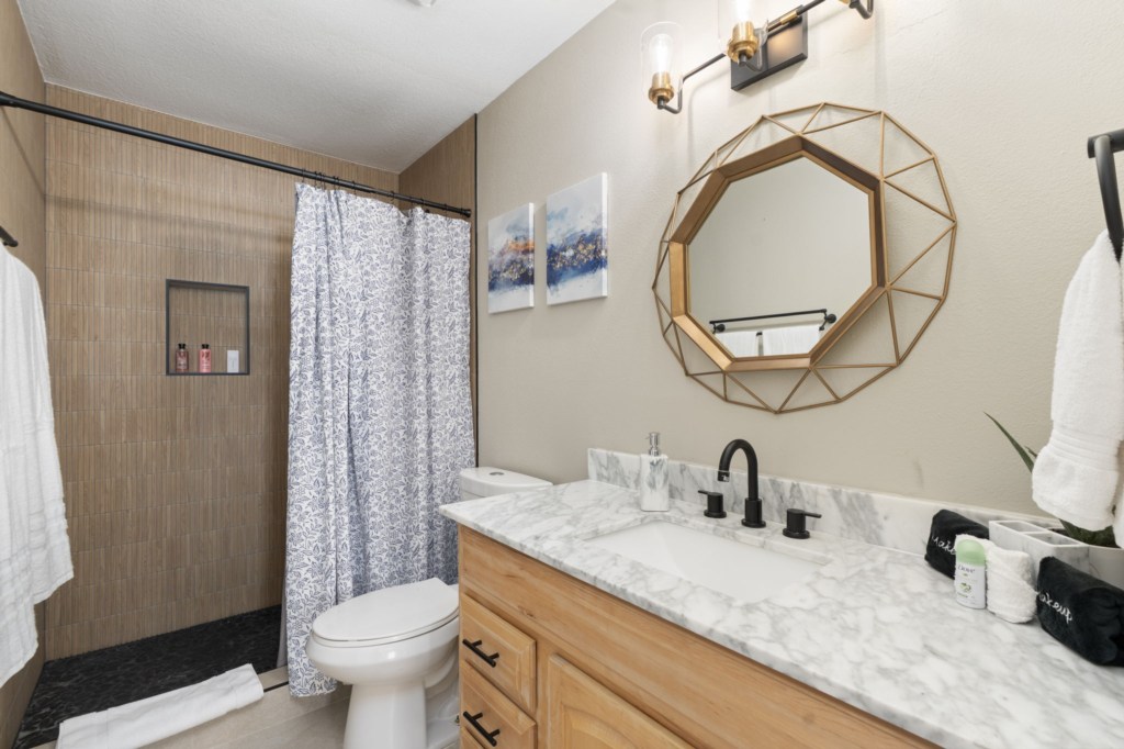 Modern bathroom with marble countertop and stylish geometric mirror.