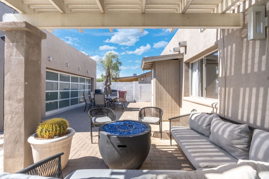 Relaxing patio with shaded seating and a modern fire pit for cozy evenings.