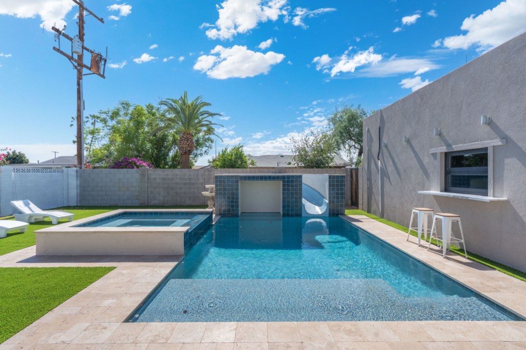 Private pool with slide and hot tub, perfect for sunny relaxation.