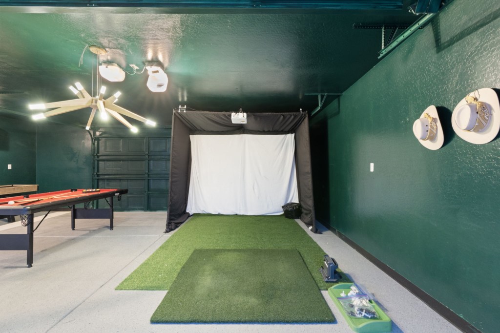 Modern games room with golf simulator and pool table for endless entertainment.