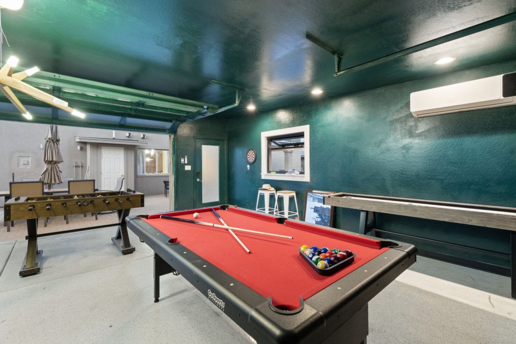 Spacious game room with pool table, foosball, and bar seating for fun-filled gatherings.