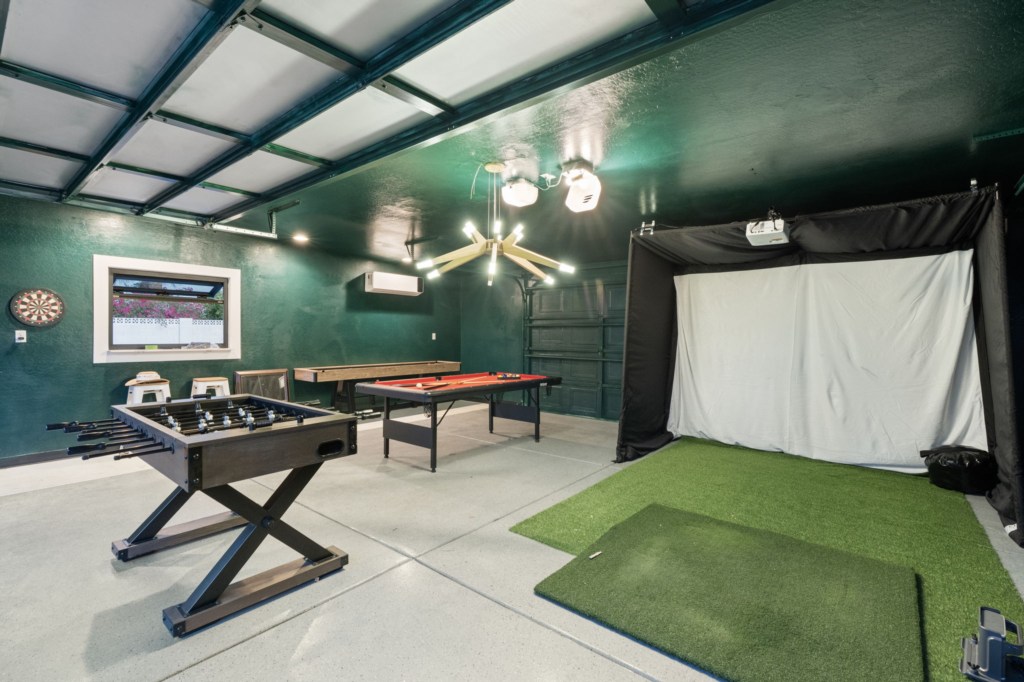 Fun games room with foosball, pool table, and golf simulator for endless entertainment.