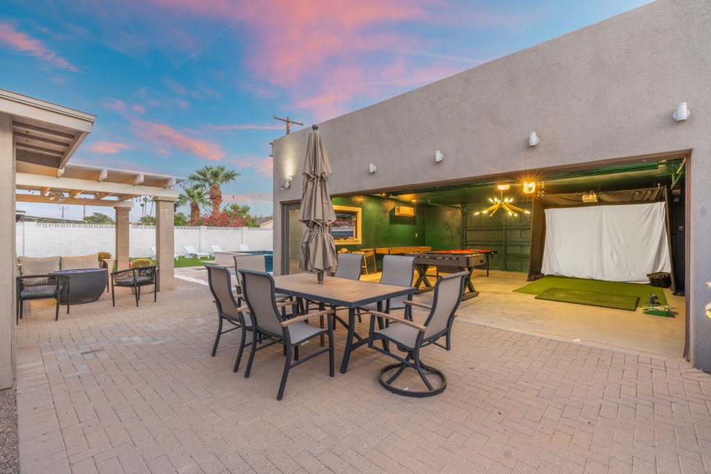 Outdoor dining area with adjacent games room and golf simulator, perfect for entertaining.