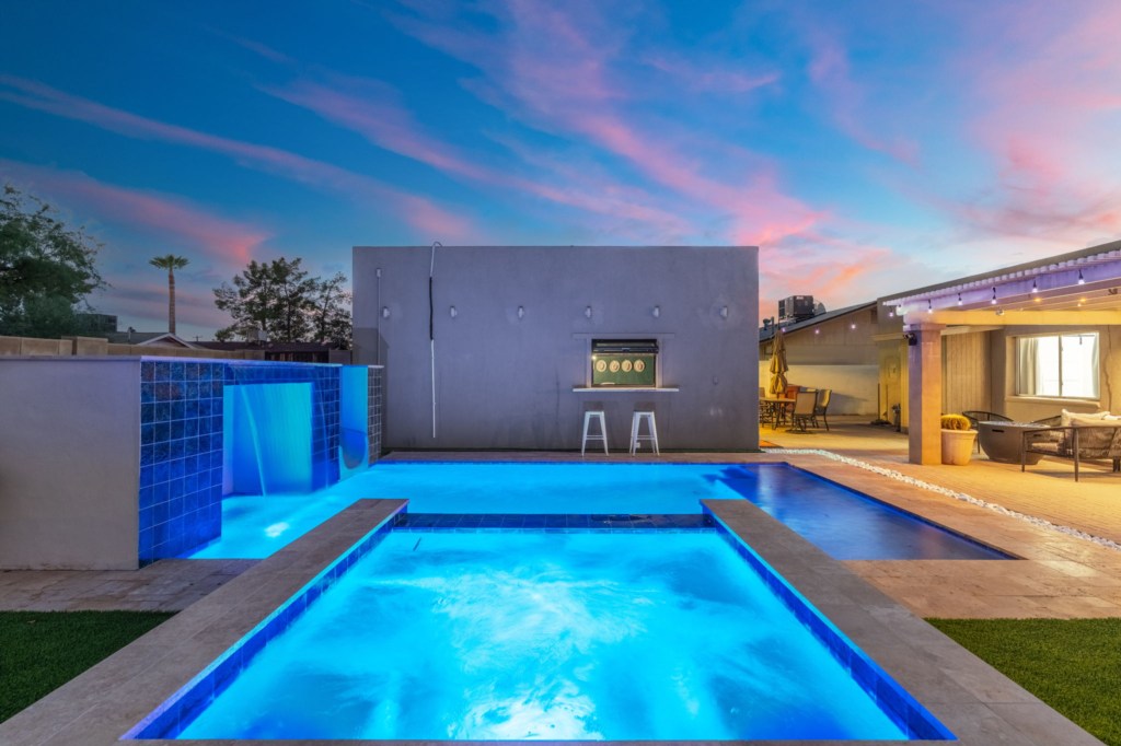 Modern outdoor pool with waterfall feature, perfect for relaxing evenings under the sunset.